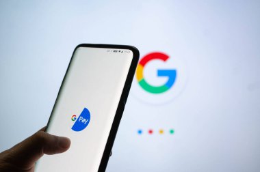 Google Pay uygulaması Google sembollü beyaz ekranın önündeki bir cep telefonuna bağlandı
