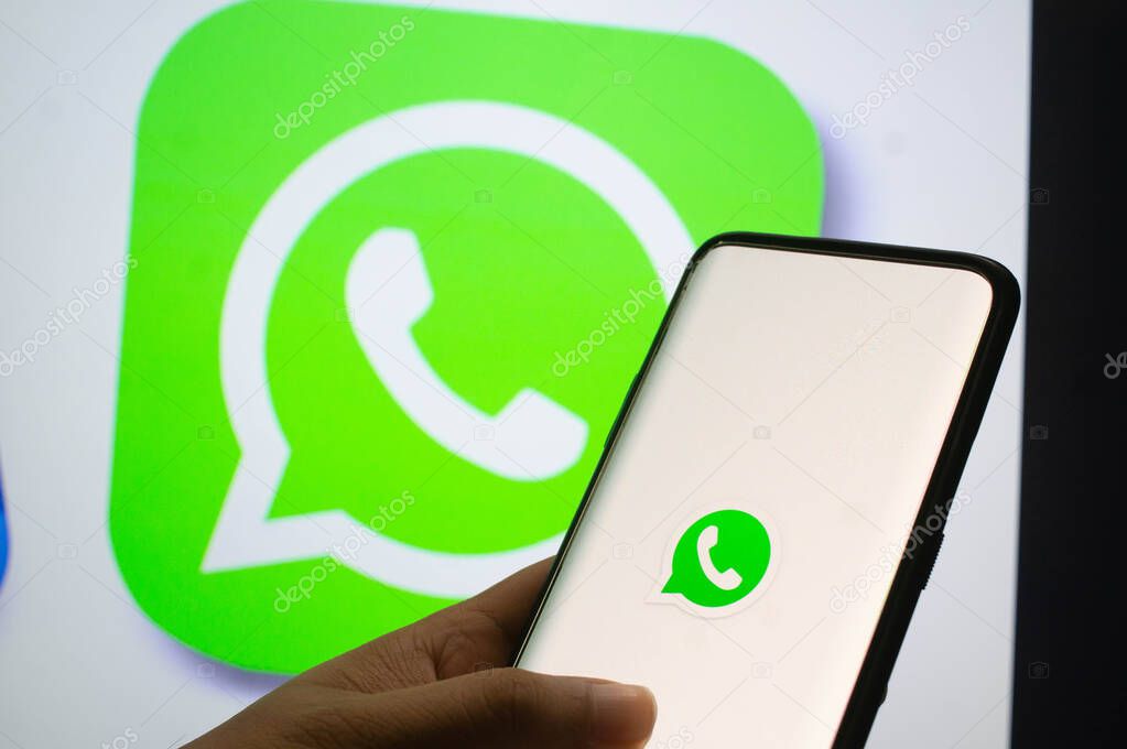 Jaipur, India, Circa 2020 - A mobile logged into the whatsapp mobile application infront of the white light board with whatsapp logo on it. The background board is brightly lit. The screen shows the