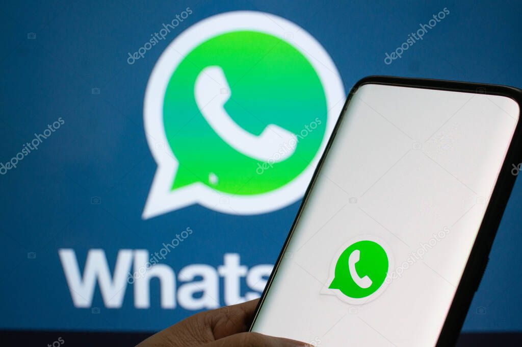 Jaipur, India, Circa 2020 - A mobile logged into the whatsapp mobile application infront of the white light board with whatsapp logo on it. The background board is brightly lit. The screen shows the