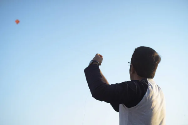 Par-dessus le coup d'épaule du jeune homme indien volant un cerf-volant en tirant sur le fil sur la fête de makar sankranti uttarayana jour de l'indépendance avec le cerf-volant hors foyer dans la distance descendant — Photo