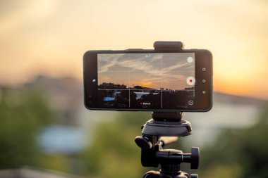 Profesyonel bir çekim için bir DSLR 'ın yerini alarak ekranda görüldüğü üzere metro istasyonu ve trenle gün batımını yakalamak için bir tripoda yerleştirildi.