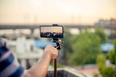 Profesyonel bir çekim için bir DSLR 'ın yerini alarak ekranda görüldüğü üzere metro istasyonu ve trenle gün batımını yakalamak için bir tripoda yerleştirildi.