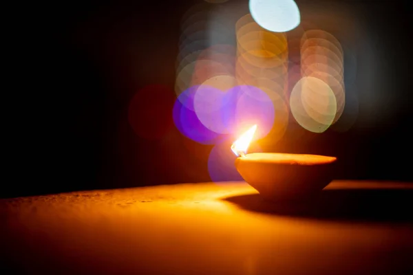 Schwenken seitlicher Ebene Aufnahme von Diya mit Flamme flackert und blinkt aus dem Fokus Bokeh String Lichter im Hintergrund auf dem hinduistischen Fest des Diwali — Stockfoto