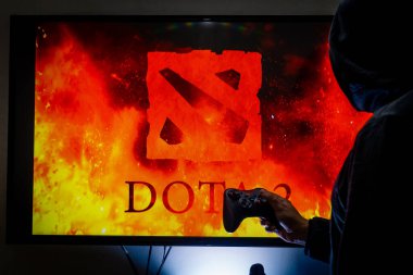 Buhar kontrol cihazı tutan ve popüler DOTA 2 oyununu bir televizyon ve PC 'de oynayan adam.