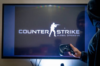 Elinde buhar kontrol cihazı olan bir adam TV ve PC 'de popüler bir video oyunu sayacı vuruşu yapıyor.