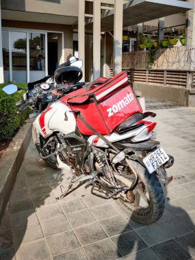 Kırmızı Zomato çantalı motosiklet sürücüsü hızlı büyüyen tek boynuzlu at teknolojisi için bir şehir kompleksine yiyecek getiriyor.