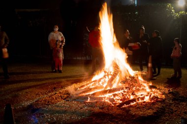 Kadın erkek aileler, Hindistan 'daki Lohri Holi festivalinde yanan dev odun ateşinin etrafında duruyorlar.