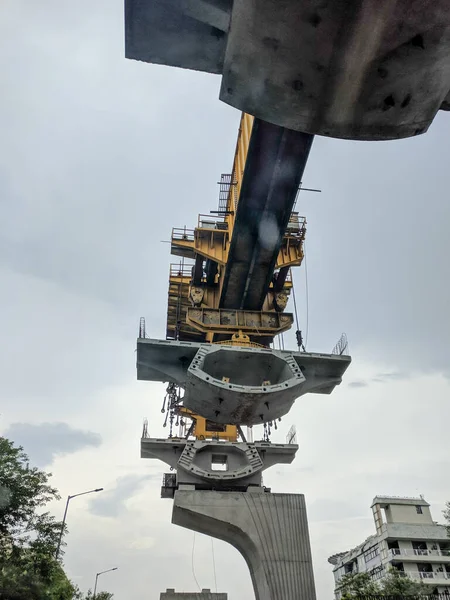 Ein Blick auf den Bau einer U-Bahn-Brücke mit modularen Betonringen und einem Kran auf einer belebten Straße bei Regen — Stockfoto