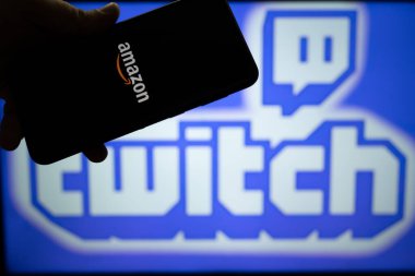 Elinde Amazon logosu olan ve arka planda seğiren platform adı ve logosu olan bir adam bu platformu tam zamanlı çalışan flamalarla gösteriyor.