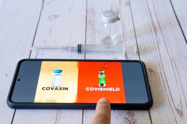 Cep telefonunda Covid 19 Coronavirus aşısı yan tarafında şırınga ve şişe olan Covishield Covaxin 'i gösteriyor.