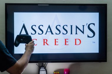 Suikastçılar oyununu yükleyen bir ekranın önünde buhar kontrolörü tutan adam, birden fazla kurulum içeren bir aksiyon macera oyunu yarattı