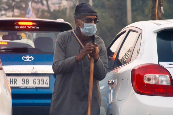 Vieja pobreza golpeada desesperado hombre hambriento mendigando en la calle con una máscara durante el mortal coronavirus covid 19 pandemia como la gente se queda en sus hogares y la gente con medios limitados sufren —  Fotos de Stock