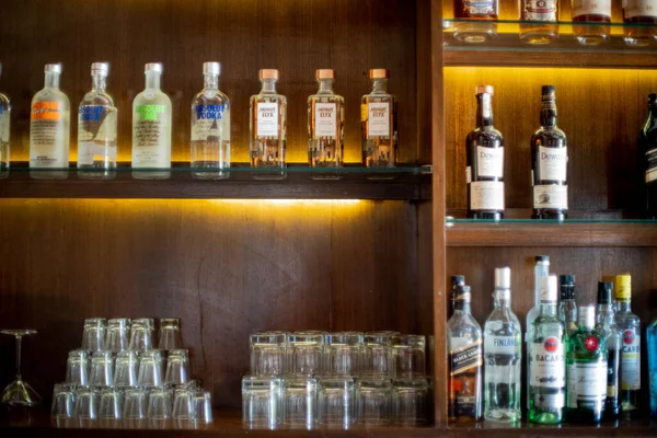 Viski, cin, rom, votka ve daha fazlasının likör şişeleriyle dolu bir bar otelinin ahşap rafının yumuşak odak noktası.
