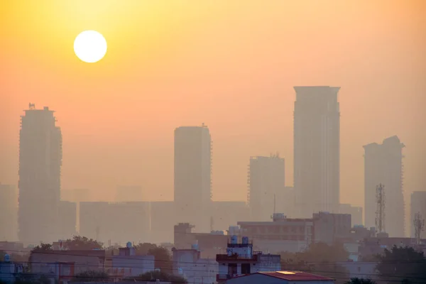 在海得拉巴古尔冈和其他印度城市，太阳升起在雾蒙蒙的摩天大楼上，有多层高楼，房屋较小 — 图库照片