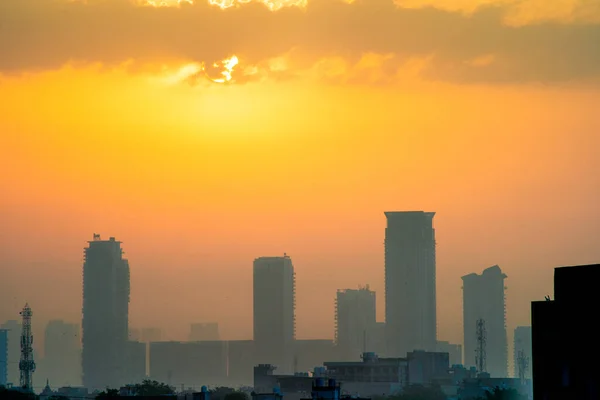 在印度的季风中，雾蒙蒙的黄昏黎明时分，阳光普照，雾蒙蒙的摩天大楼笼罩着多层的古尔冈、木乃伊、斑马线的城市景观 — 图库照片