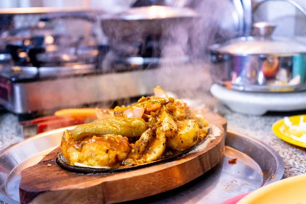 Plato asiático indio servido en una bandeja de madera con un plato caliente de hierro que hace que las verduras como el arroz de patata repollo para cocinar y emiten humo como el plato se sirve a la gente — Foto de Stock