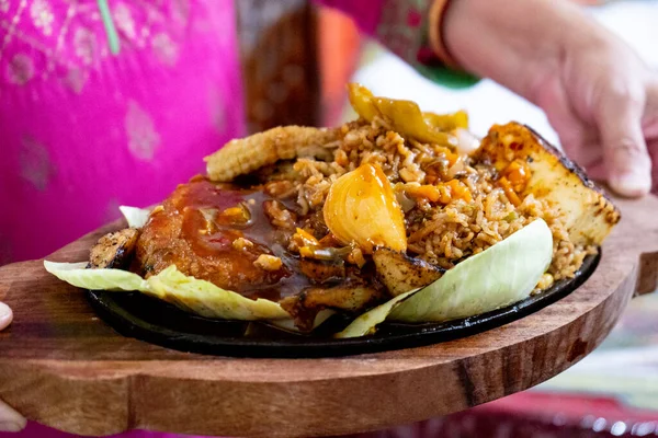 Affumicatrice sparata con verdure, carne, cavolo di pollo e peperoncini posti su un piatto di ferro caldo e serviti su un vassoio di legno — Foto Stock