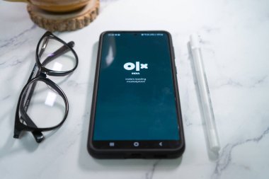 Asya 'daki eBay ve craigslist gibi en büyük ikinci el satış yeri olan Olx Indias' ın logosunu gösteren cep telefonunun düz açılı görüntüsü