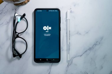 Asya 'daki eBay ve craigslist gibi en büyük ikinci el satış yeri olan Olx Indias' ın logosunu gösteren cep telefonunun düz açılı görüntüsü