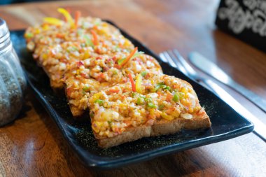 Sarımsaklı ekmek dilimleri, tereyağlı mozzarella sebze soğanlı dolmalık biber, siyah bir tabakta tuz biberi ve kekik otu ile birlikte Hindistan 'da bir delhi kafede.