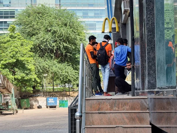 Delivery boys riders from companies like swiggy shadowfax zomato standing at a McDonalds takeaway for online food delivery by e-commerce app unicorns — Φωτογραφία Αρχείου