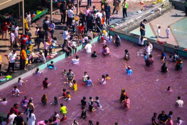 Delhi, Hindistan - 14. Mar 2025: Pembe renklerle dolu bir yüzme havuzunda Hindu Holi Festivali oynayan insanların yakınlaştırılmış görüntüsü