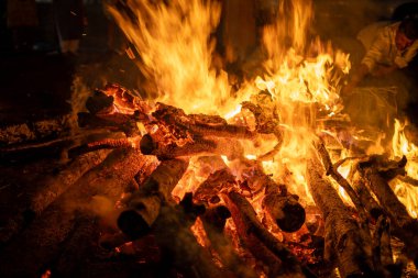 Açık hava kampı, kış geceleri ve Hindu Holi Festivali 'ni gösteren parlak turuncu bir alevle kül olmuş ahşap odunların makro çekimlerini kapat.