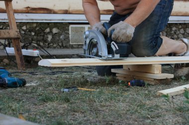 Adamın biri elektrikli testere ile tahta kesiyor.