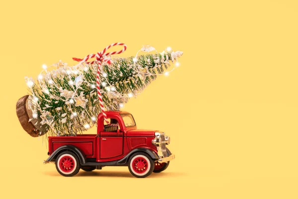 Kamyon gövdesinde parıldayan Noel ağacı ışıklarıyla altın arka planda kırmızı küçük bir oyuncak kamyon. Teslimat, Noel, yeni yıl konsepti. Boşluğu kopyala, seçici odak.