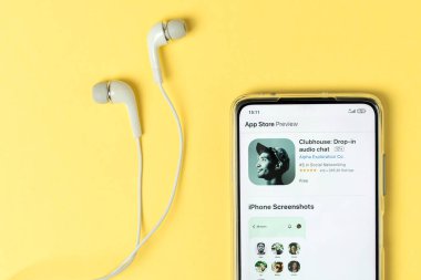 Severodvinsk, Rusya - 17 Şubat 2021: Kulüp binası ses uygulaması görüntüsü akıllı telefon ve kulaklıklar sarı arka planda. 2021 trendi. Üst manzara, düz uzanma.