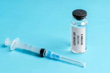 Rus aşısı Sputnik V ve mavi arka planda şırınga enjeksiyonu. Coronavirus aşısı. COVID-19 aşısı. Sağlık ve tıbbi konsept. Boşluğu kopyala, ön görünüm.
