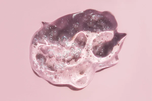 Hyaluronik asit serum dokusu. Pastel pembe arka planda güzellik derisi sıvı jölesi.