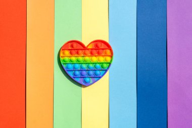 Kalp şeklinde renkli anti-stres oyuncağı. Duyusal oyuncak. Gökkuşağı arka planına yerleştir. Üst görünüm, düz görünüm, kopyalama alanı, sert ışık