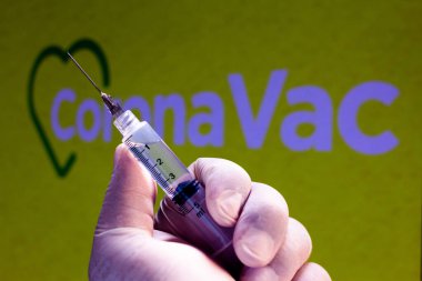 10 Kasım 2020, Brezilya. Bu resimde tıbbi şırınga arka planda CoronaVac logosu sergilenmektedir. Sinovac ve Butantan Enstitüsü Brezilya 'da aşıyı test ediyor