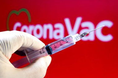 10 Kasım 2020, Brezilya. Bu resimde tıbbi şırınga arka planda CoronaVac logosu sergilenmektedir. Sinovac ve Butantan Enstitüsü Brezilya 'da aşıyı test ediyor