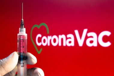 10 Kasım 2020, Brezilya. Bu resimde tıbbi şırınga arka planda CoronaVac logosu sergilenmektedir. Sinovac ve Butantan Enstitüsü Brezilya 'da aşıyı test ediyor