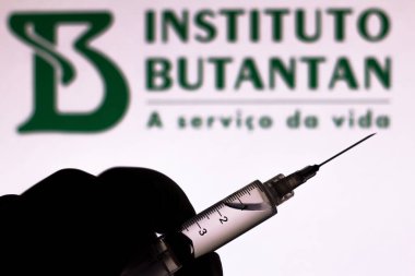November 10, 2020, Brazil. In this photo illustration the medical syringe (coronavirus vaccine) is seen with Instituto Butantan company logo displayed on a screen in the background clipart