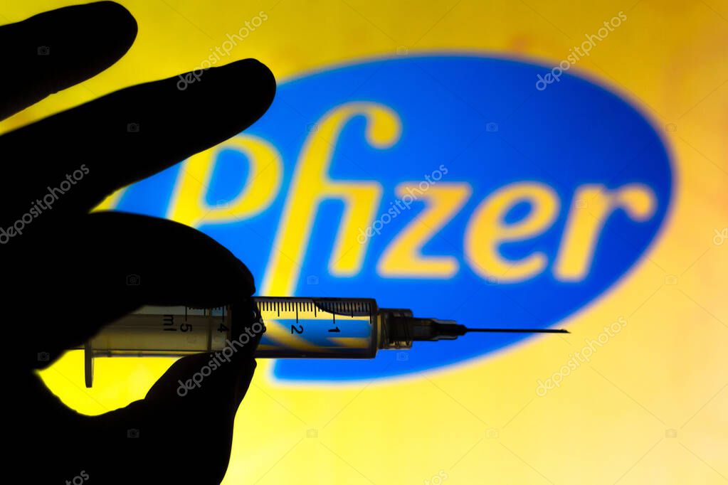 November 11, 2020, Brazil. In this photo illustration the medical syringe (coronavirus vaccine) is seen with Pfizer company logo displayed on a screen in the background