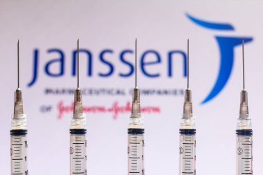 December 4, 2020, Brazil. In this photo illustration various medical syringes is seen with Janssen Pharmaceutica company logo displayed on a screen in the background clipart
