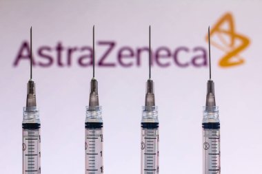 December 4, 2020, Brazil. In this photo illustration various medical syringes is seen with AstraZeneca company logo displayed on a screen in the background clipart