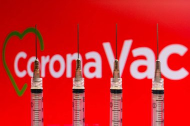December 4, 2020, Brazil. In this photo illustration various medical syringes is seen with Coronavac company logo displayed on a screen in the background clipart
