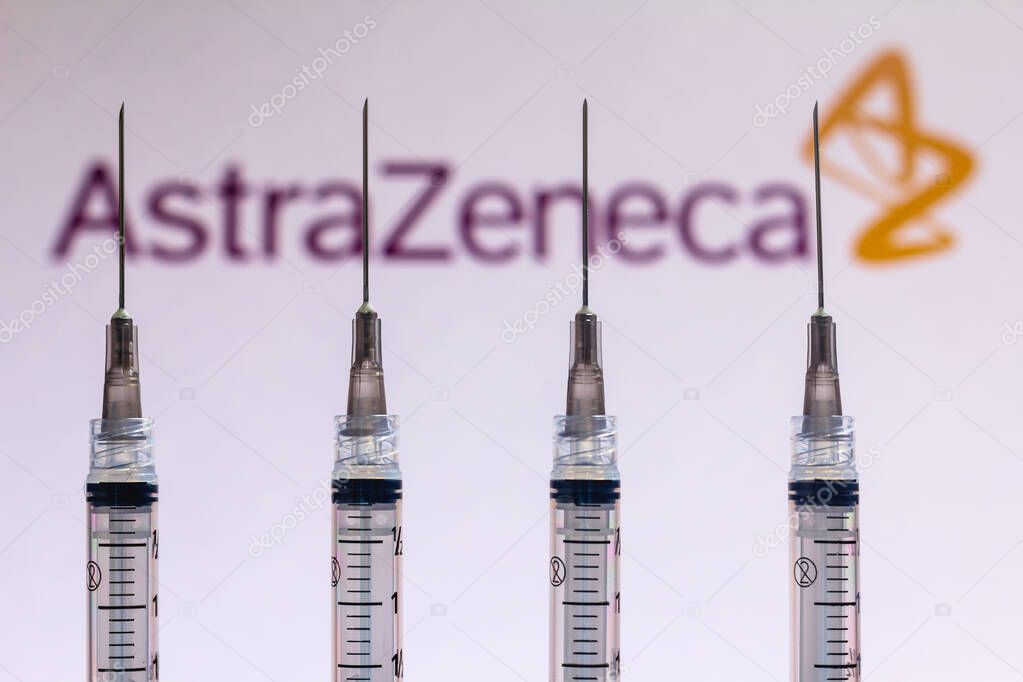 December 4, 2020, Brazil. In this photo illustration various medical syringes is seen with AstraZeneca company logo displayed on a screen in the background