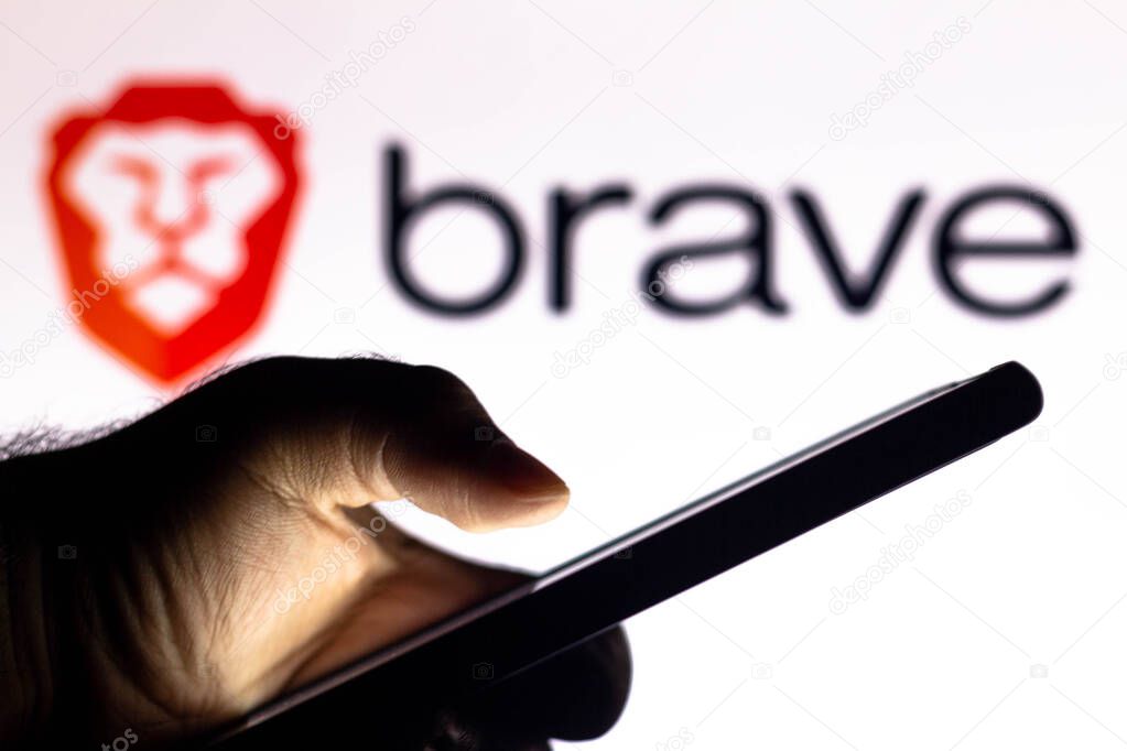 January 20, 2021, Brazil. In this photo illustration the Brave Browser logo seen in the background of a silhouette hand holding a mobile phone