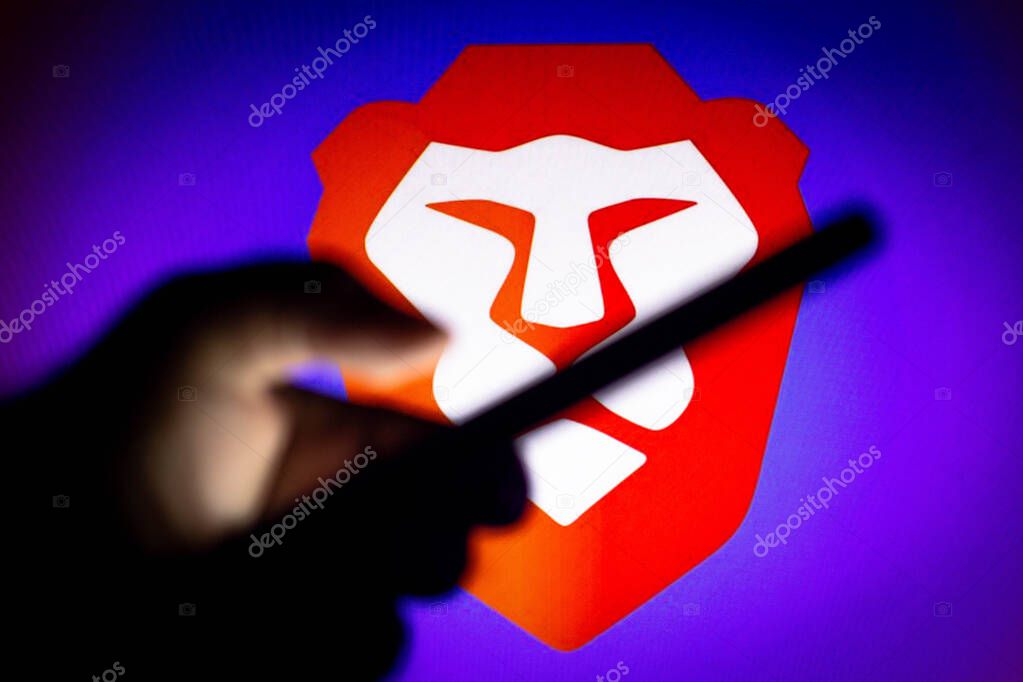 January 20, 2021, Brazil. In this photo illustration the Brave Browser logo seen in the background of a silhouette hand holding a mobile phone