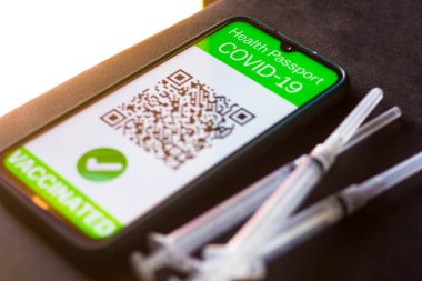 5 Nisan 2021, Brezilya. Bu resimde, bir aşı şırıngasının yanındaki akıllı telefon ekranında görülen sembolik COVID-19 sağlık pasaportu