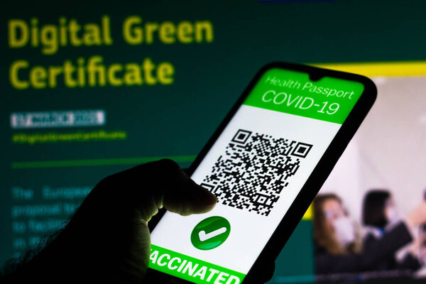 April 5, 2021, Brazil. In this photo illustration, a symbolic COVID-19 health passport seen displayed on a smartphone screen in front of the European Commission information about a proposal to create a Digital Green Certificate
