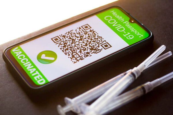 April 5, 2021, Brazil. In this photo illustration, a symbolic COVID-19 health passport seen on a smartphone screen next to a vaccination syringe