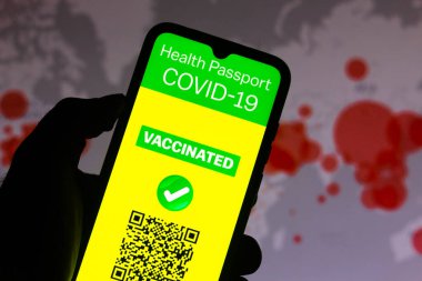 6 Nisan 2021, Brezilya. Bu resimde COVID-19 'un aşı pasaport başvurusu akıllı telefon ekranında gösteriliyor. Arka planda, dünyada koronavirüs vakalarının olduğu bir harita var.