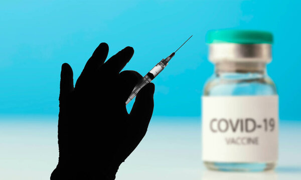 April 12, 2021, Brazil. In this photo illustration the medical syringe is seen with the Covid-19 vaccine vial displayed on a screen in the background
