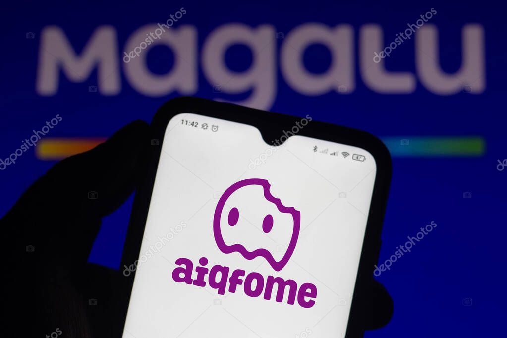 April 15, 2021, Brazil. In this photo illustration the Aiqfome logo seen displayed on a smartphone screen with the logo of Magalu (Magazine Luiza) in the background
